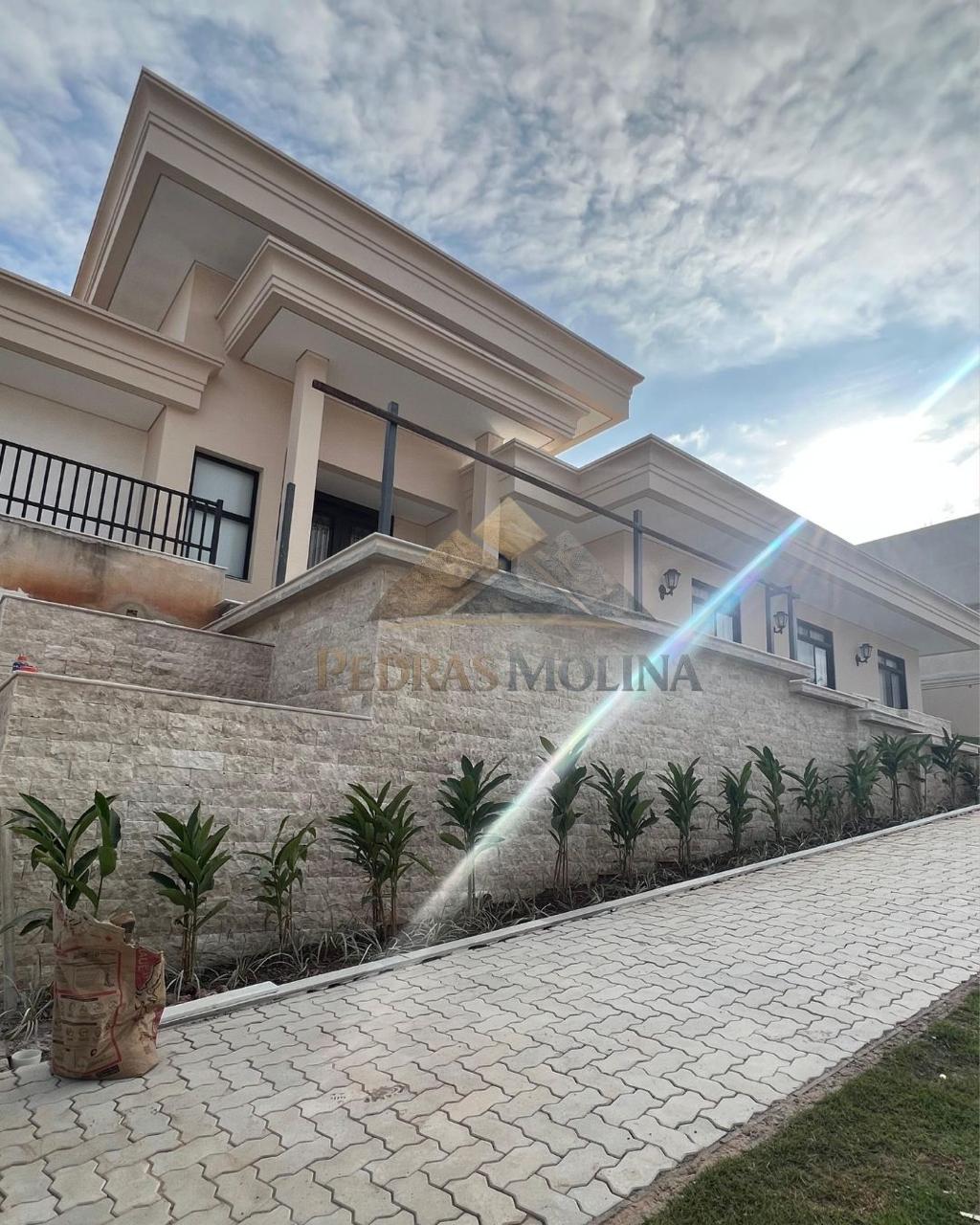 Fachada de residência com muro revestido em pedra natural